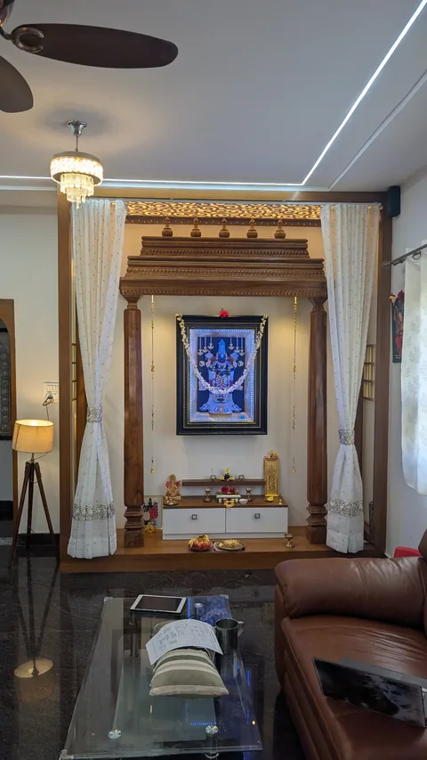 The completed carved puja unit with finished lighting, curtains and lower storage at the same customer's home.