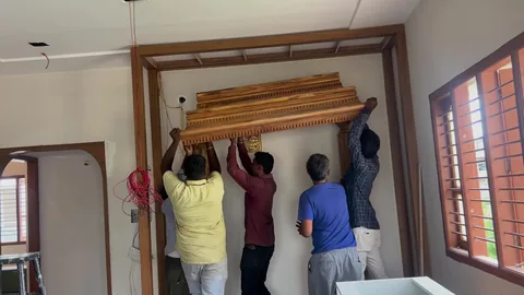 Grihala team lifting and fitting the carved top of a puja unit at a customer's home.